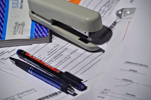 Ondernemer bekijkt openstaande factuur op bureau met laptop en administratie